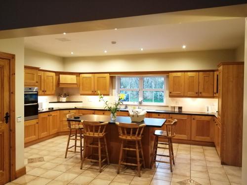 uma cozinha com armários de madeira e uma ilha com bancos de bar em Rosswood House em Donegal