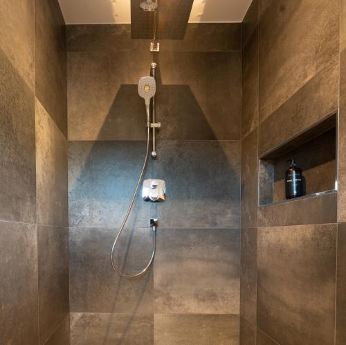 La salle de bains est pourvue d'une douche avec un pommeau de douche. dans l'établissement Apartment Waldherz, à Wald im Pinzgau