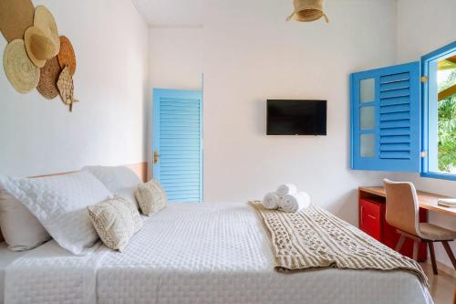 a bedroom with a bed with blue shutters and a desk at Pousada Sabina in Barra Grande