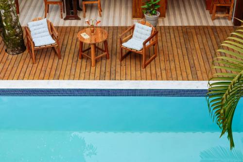 a deck with chairs and a table next to a pool at Pousada Sabina in Barra Grande