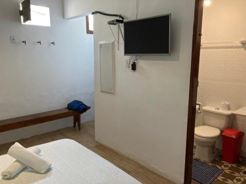 a bathroom with a toilet and a tv on the wall at Mangue Seco Lodge - Experiência Gastronômica in Mangue Sêco