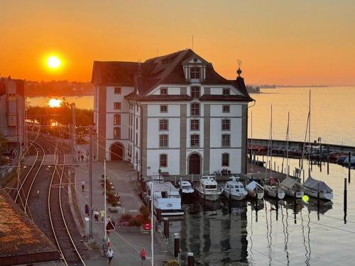 a large building with boats in a marina at sunset at Lakeside Apartments Rorschach - easy self check-in in Rorschach