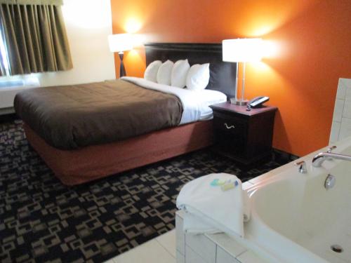 a hotel room with a bed and a bath tub at AmericInn by Wyndham Wausau in Weston