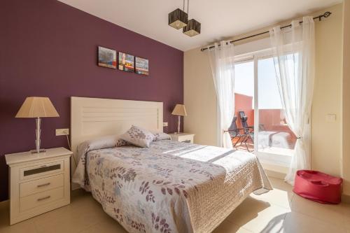 um quarto com uma cama com paredes roxas e uma janela em Apartmento en Torrox Costa em Torrox Costa