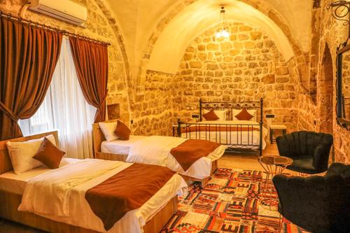 ein Schlafzimmer mit 2 Betten und einem Stuhl in einem Zimmer in der Unterkunft Nostalji in Mardin