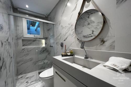 フロリアノポリスにあるCasa moderna com piscina em Floripa - caminho das praiasの洗面台と鏡のある白いバスルーム