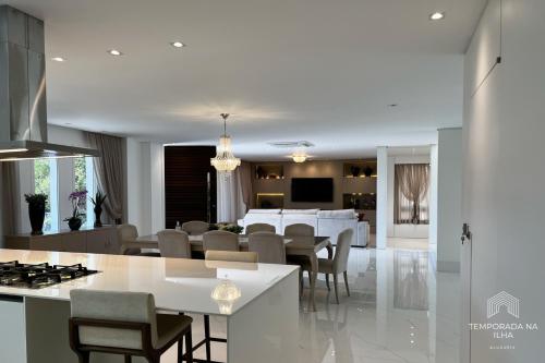 フロリアノポリスにあるCasa moderna com piscina em Floripa - caminho das praiasのテーブルと椅子のあるキッチンとリビングルーム