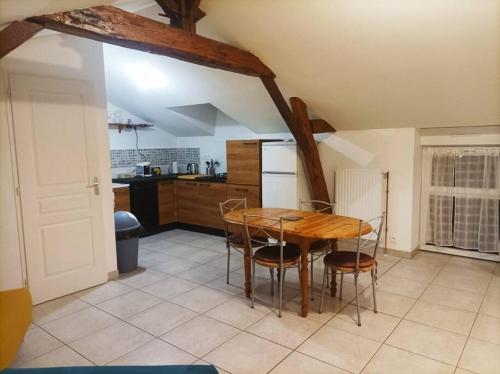 una cocina con mesa de madera y sillas. en Studio en pleine campagne avec jardin privatif, en Bournand