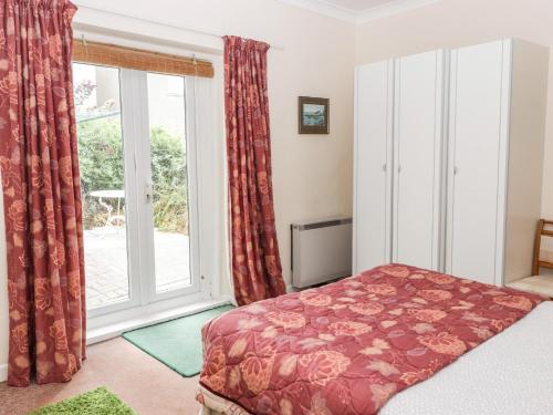 een slaapkamer met een bed en een groot raam bij Gwylan Apartment in Tenby
