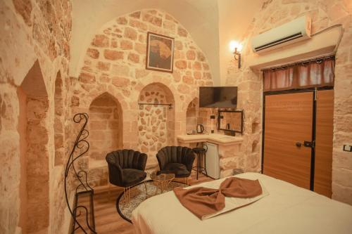 ein Schlafzimmer mit einer Steinmauer mit einem Bett und Stühlen in der Unterkunft Nostalji in Mardin