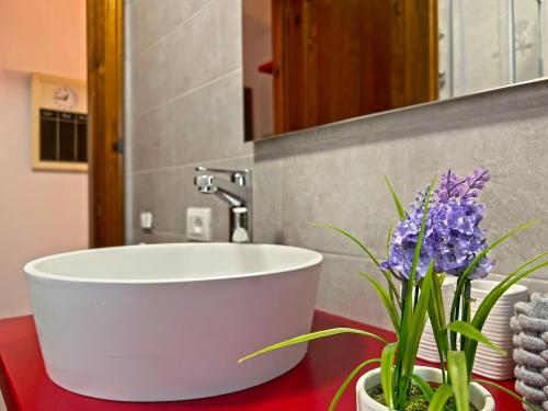 a bathroom with a white tub and purple flowers on a counter at Mandi Mandi a Tarvisio in Tarvisio