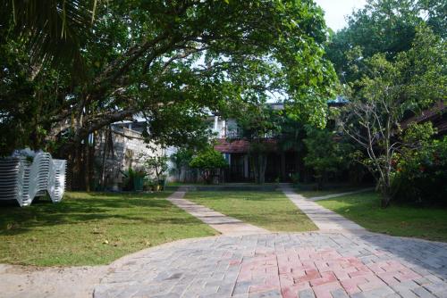 a brick path in front of a house with a tree at Turtle Bay Beach Resort in Mirissa