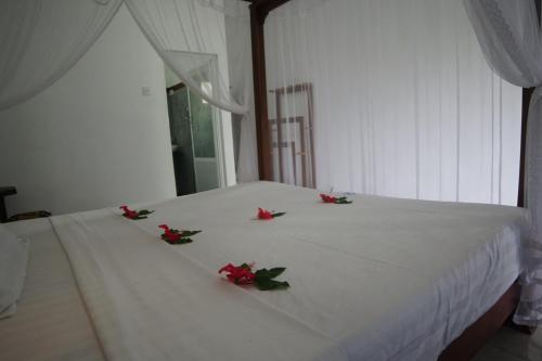 a white bed with red flowers on it at Turtle Bay Beach Resort in Mirissa