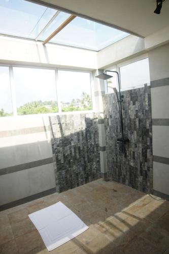 a bathroom with a shower with a window at Turtle Bay Beach Resort in Mirissa