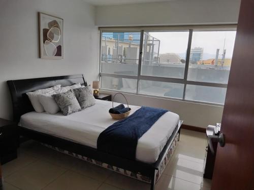 1 dormitorio con 1 cama y ventana grande en Ecusuites TorreSol I Parking, en Guayaquil