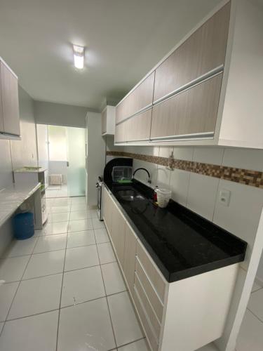 uma cozinha com armários brancos e um balcão preto em Apartamento no bairro universitário em Caruaru