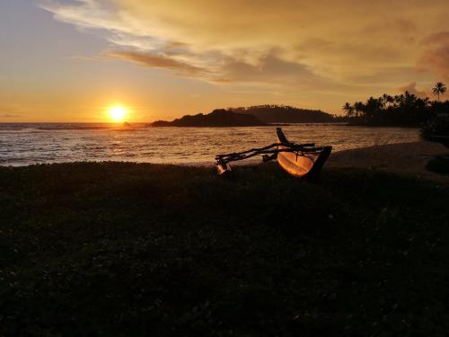 a bench on the beach with the sunset in the background at Turtle Bay Beach Resort in Mirissa