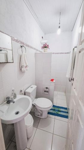 a white bathroom with a toilet and a sink at Casa Areal Boipeba in Ilha de Boipeba