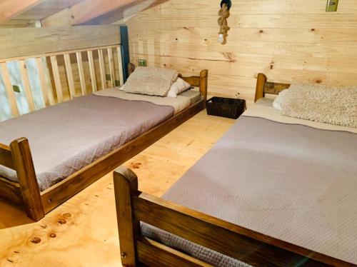 two beds in a room with wooden walls at CasaLoft Caicai in Licán Ray