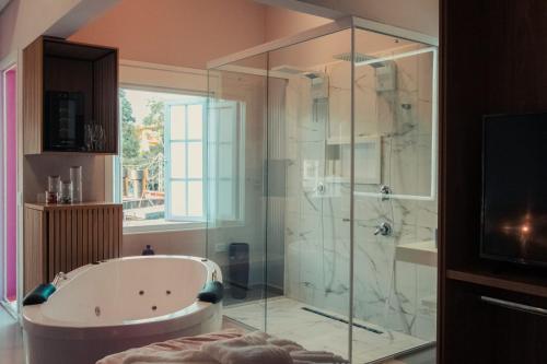 a bathroom with a tub and a glass shower at Esquina Brotense_Hospedagem de charme in Brotas