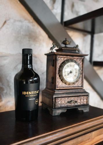 a bottle of wine next to a clock on a table at Hotel Hort De Fortunyo in Arnés