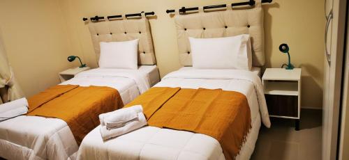 1 dormitorio con 2 camas con sábanas blancas y naranjas en Apart hotel Florida, en Ciudad del Este