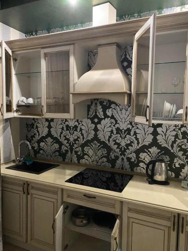 a kitchen with white cabinets and black and white wallpaper at Fontush Boutique Hotel in Ivano-Frankivsʼk