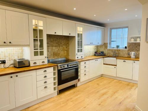 a kitchen with white cabinets and wooden floors at Entire Home between London and Kent- Mulberry House in Kent