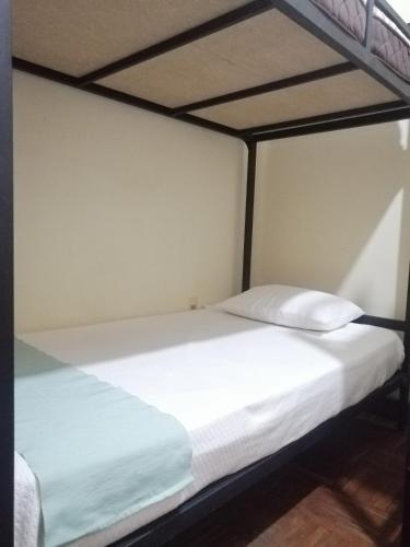 a bed with white sheets and pillows on it at Hostel Cultural Pata y Perro in Tarija