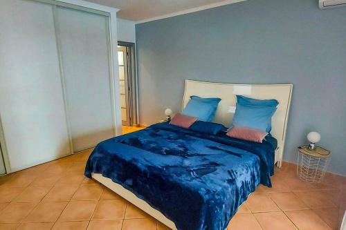 a bedroom with a blue bed with blue sheets and pillows at Villa Aloes: Vue mer et calme à 2 pas de la plage in Le Diamant