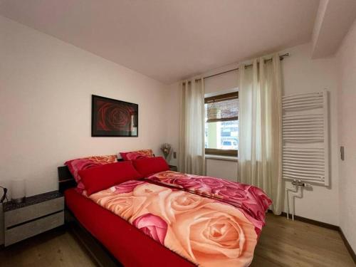 a bedroom with a large bed with red sheets and a window at Schöne Eigentumswohnung optional mit Sauna Nutzung in Villingen-Schwenningen