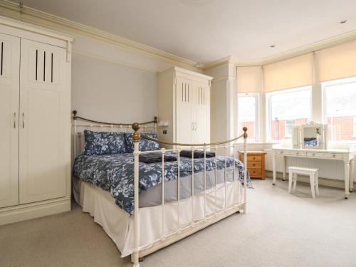 a bedroom with a bed and a desk and windows at Yewdale in Lytham St Annes