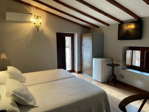 a bedroom with a bed and a television on the wall at Apartamento rural jama in Cilleros