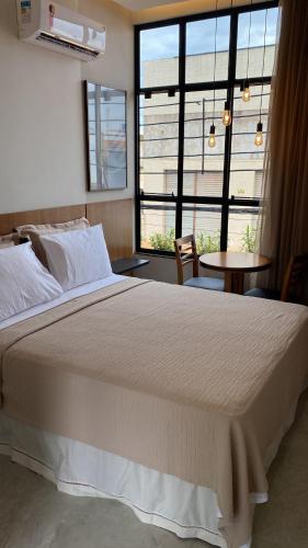 a bedroom with a large bed and a large window at Hotel Goiano in Estreito