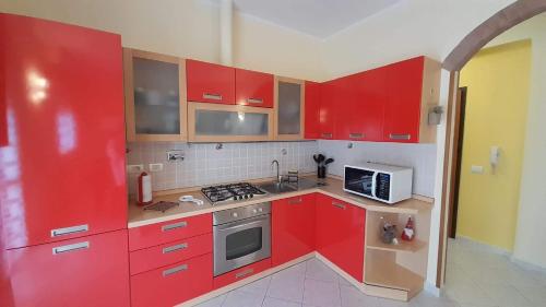 cocina con armarios rojos y microondas en CASA DEL BORGO, en San Venanzio