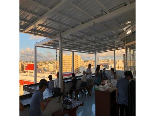 un groupe de personnes assises dans une pièce dotée d'une grande fenêtre dans l'établissement Sunset Hills Inn Naha - Vacation STAY 77494v, à Naha