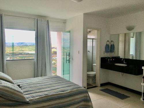 um quarto com uma cama e uma casa de banho com um lavatório em Apartamento Mirante de Escarpas 1703 em Capitólio