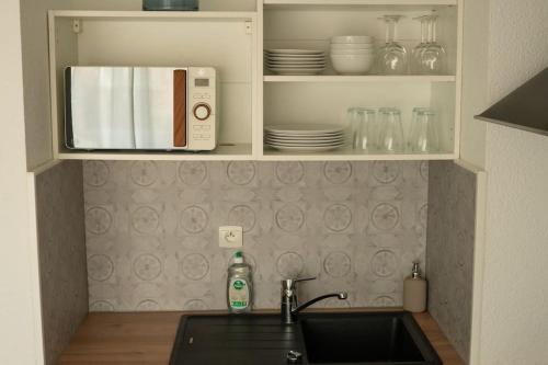 a kitchen counter with a sink and a microwave at Studio Ouistreham entre centre-ville et plages in Ouistreham