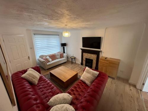 a living room with a red couch and a fireplace at Beautiful 4 bedroom home 3 bathrooms, Excellent location, Family, Group, Corporate, Contractor in Thamesmead