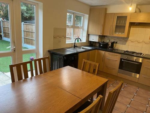 a kitchen with a wooden table and a table and chairs at Beautiful 4 bedroom home 3 bathrooms, Excellent location, Family, Group, Corporate, Contractor in Thamesmead
