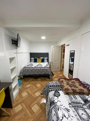 two beds in a room with wooden floors at Hostal Familiar S&G in Santiago