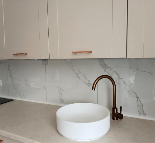 a white kitchen with a sink and a faucet at Gallery Apartment Bielefeld in Bielefeld