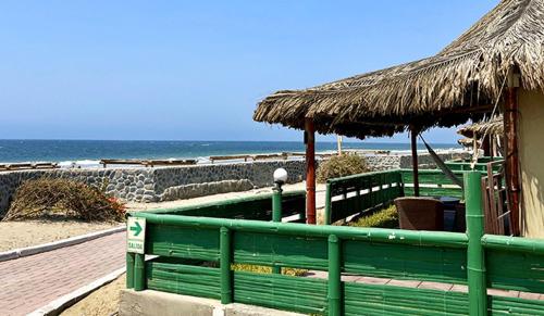 un banco verde junto a una playa con una cabaña en Vichayito Bungalows & Carpas, en Vichayito