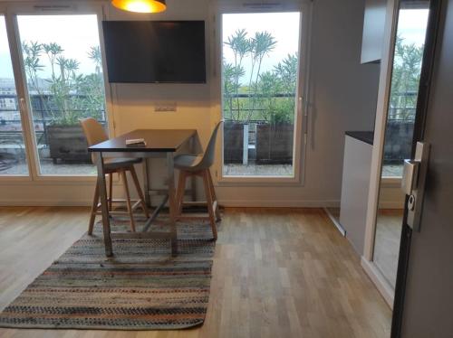 a dining room with a table and chairs and a television at Studio avec terrasse proche des transports. in Issy-les-Moulineaux