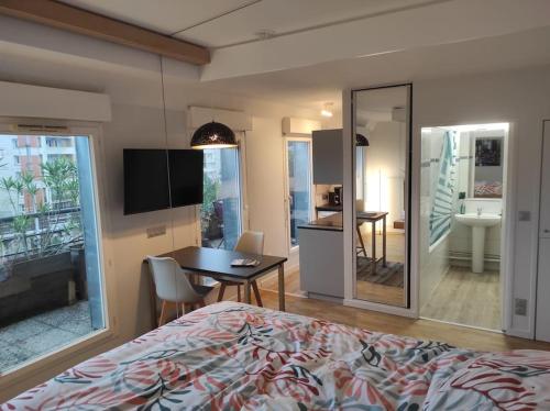 um quarto com uma cama, uma mesa e uma cozinha em Studio avec terrasse proche des transports. em Issy-les-Moulineaux