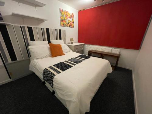 a bedroom with a large bed and a red wall at GoldenTriangleCityRooms in Norwich