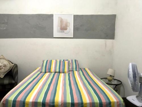 um quarto com uma cama com lençóis coloridos listrados em Pousada Cisne Branco em Natal