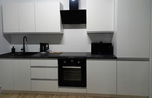 uma cozinha com armários brancos e um forno preto em Apartament Różana Piątka em Kutno