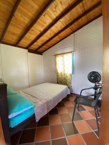 a small bedroom with a bed and a chair at Cabaña Alcaravanes. in San Vicente de Chucurí
