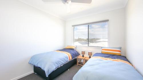 two beds in a room with a window at Surf and Dunes in Yamba